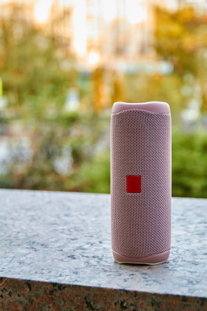 Portable pink wireless speaker in the city. Close-up, selective focus