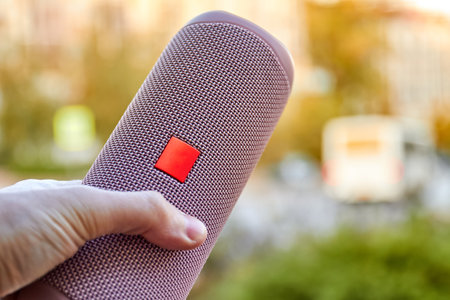 A man holding a Portable pink wireless speaker in his hand. Close-up, selective focusの写真素材