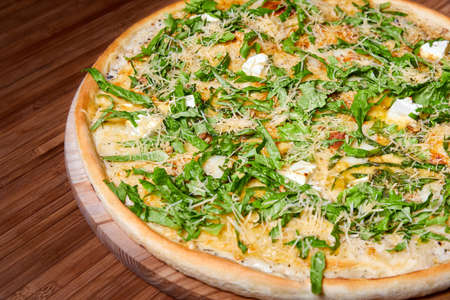 Pizza with cheeses and herbs on a wooden plate. Close-up, selective focusの写真素材