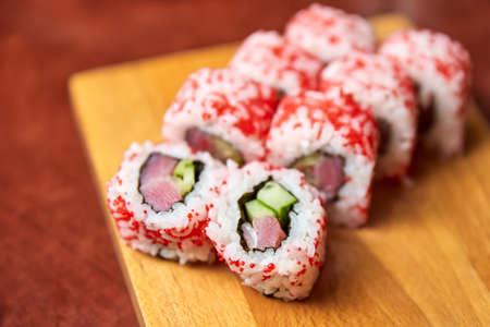 Roll with tuna and cucumber on wooden board. Close-up, selective focusの写真素材