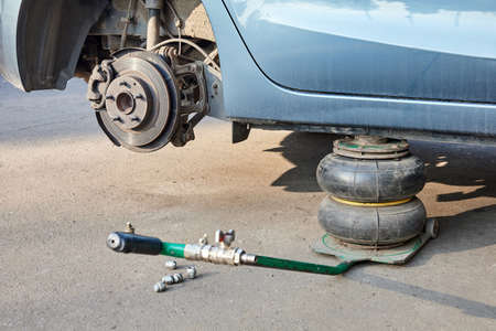Car without wheels lifted up with jacks during wheel replacement. Seasonal change of car tires.の写真素材