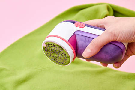 A wooman using Fabric shaver removes fabric pills from garments. Close-up, selective focusの写真素材