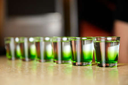 Several white-green alcoholic drinks shots on the bar counterの写真素材