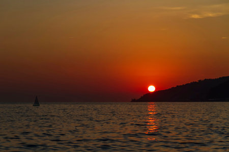 Small sailboat at sea at sunsetの写真素材