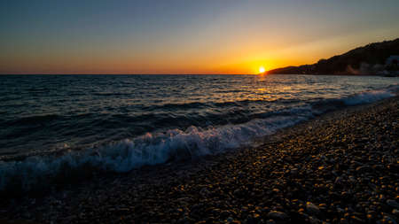 Sunset at sea. Pebble beach, wavesの写真素材