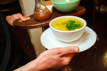The waiter holds a plate of chicken brothの写真素材