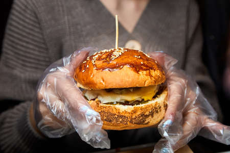 Girl holding a hamburger in her hands and getting ready to eat it. Close-up, selective focusの写真素材