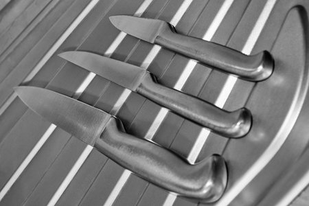 Set of metal kitchen knives on a chrome surface. Cooking concept. Black and white photoの写真素材