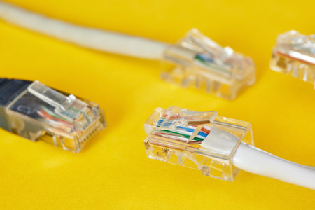 Ethernet cables with RJ45 plug on yellow background. Close-up, selective focus
