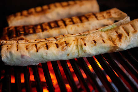 Lavash with filling is baked on the grill. Close-up, selective focusの写真素材