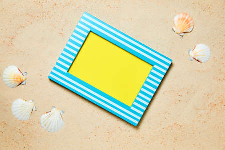 Picture frame with copy space and sea shells on sand as a summer backgroundの写真素材