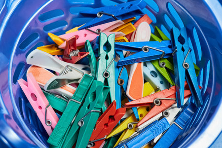Multi-colored clothespins in a plastic bucket. Close-up, selective focus
