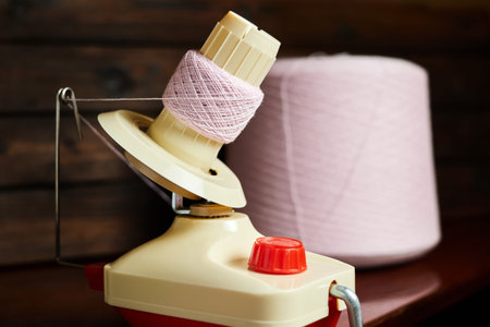 Mechanical yarn winder or reel while rewinding thread. Close-up, selective focus