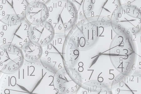 Background from set of white analog round office clocks of different sizes showing various timeの写真素材