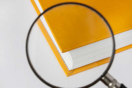 Closed yellow book with a magnifying glass. Focusing on the corner of the book. Closeup, selective focusの写真素材