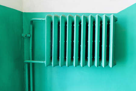Green painted heating radiator against the wall in the entrance of the apartment houseの写真素材