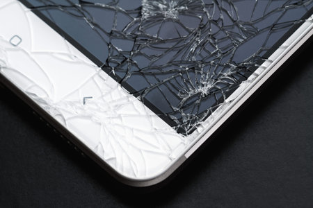 Broken display screen. Damaged smartphone glass. Closeup, dark background, selective focus