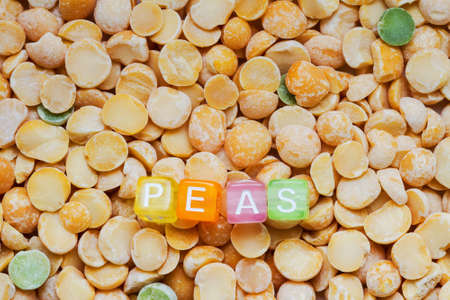 Background from peas with the inscription of peas in colored letters on cubes. Closeup, top viewの写真素材