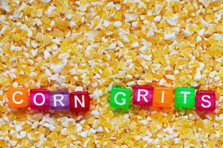 Background from corn grits with the inscription of corn grits in colored letters on cubes. Closeup, top viewの写真素材