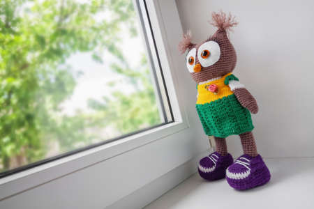 Handmade crochet toy owl near the windowの写真素材
