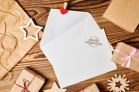 Open envelope with blank letterhead on wooden background with christmas accessories