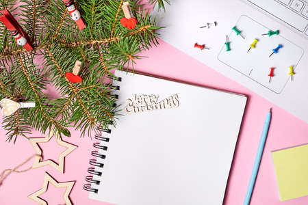 Christmas composition of open blank notepad, fir branches and laptop on pink paper backgroundの写真素材