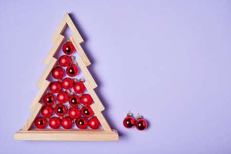 Wooden christmas tree with red christmas balls inside on pink background with copy spaceの写真素材