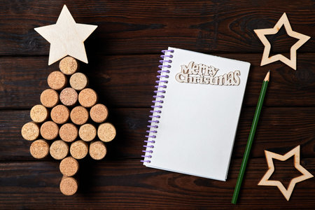 Christmas tree from wine corks with a star on top and Blank notepad on wooden background