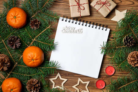 Christmas composition of Blank notepad with the inscription merry Christmas on wooden background with christmas accessoriesの写真素材
