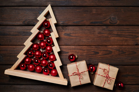 Christmas composition of gift boxes and Wooden christmas tree with red christmas balls inside on wooden backgroundの写真素材