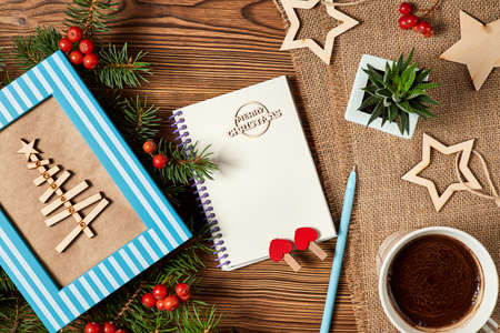 Christmas composition of open blank notepad, coffee cup, Christmas tree and Cactus on wooden...