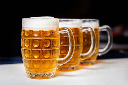 Three glasses of fresh foamy beer on the bar counterの写真素材
