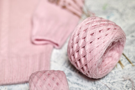 Pink knitted women's sweater with patterns and balls of thread