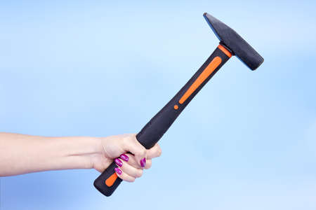 A girl holds a hammer in her hand on a blue backgroundの写真素材