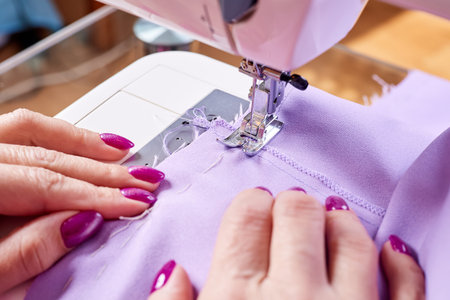 Woman sewing a dress on a sewing machine. Close up, selective focus