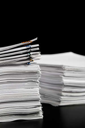 Stacks of papers with multicolored paper clips on a dark backgroundの写真素材