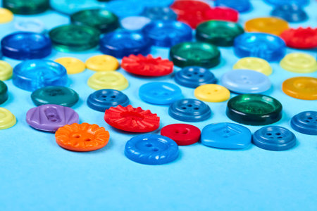 Multicolored buttons for clothes on a blue background. Close up, selective focus