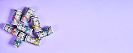 Rolled up one hundred dollar bills with rubber bands on purple background with copy spaceの写真素材