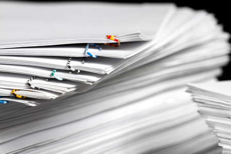 Stacks of papers with multicolored paper clips on a dark backgroundの写真素材