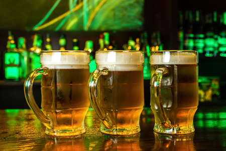Close-up of three mugs of foamy beer on the barの写真素材
