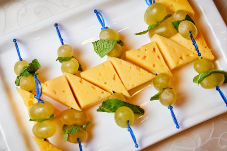 Canape on skewers with cheese and olives on a white plateの写真素材