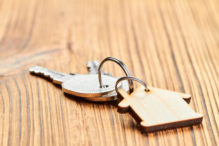 Trinket in the form of a wooden house with the keys to the apartment on wooden backgroundの写真素材