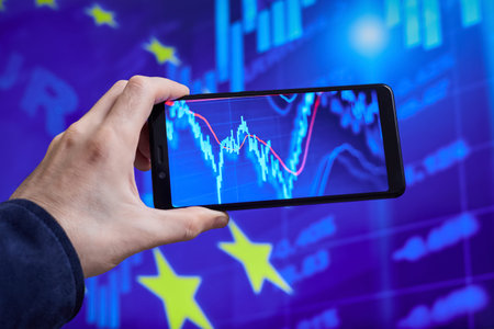 Trader analyzes stock market data in smartphone on the background of stock charts