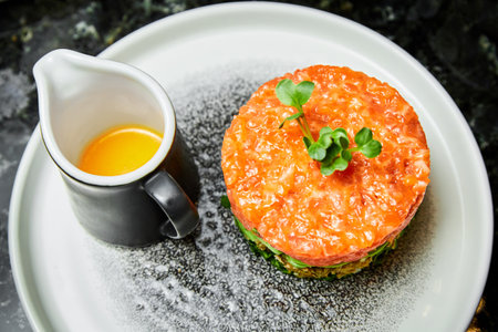 Salmon tartare with avocado on a white plate in a restaurant. Close up, selective focusの写真素材