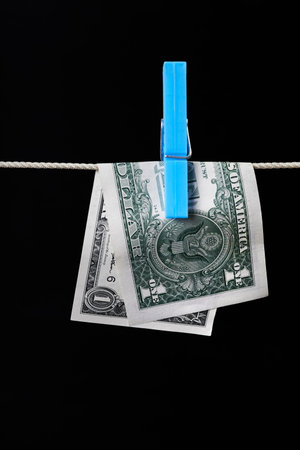 One dollar fastened with a clothespin is dried on a clothesline on a dark background