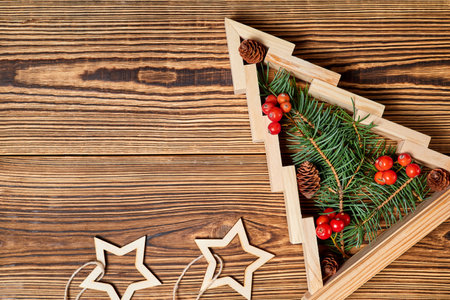 Wooden christmas tree with Fir branches inside decorated with rowan berries on wooden background with copy spaceの写真素材