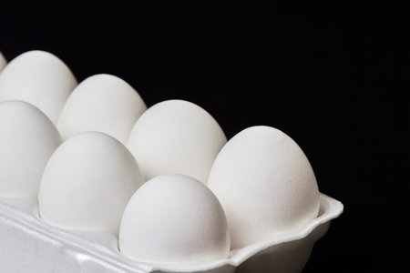 Tray with white chicken eggs on a dark background