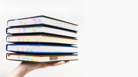 An office employee holds on his hand a stack of notebooks with colorful bookmarks on a light backgroundの写真素材