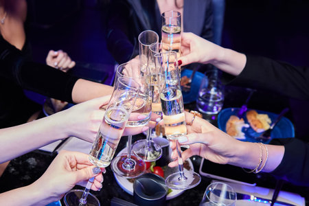 Girls in a nightclub click glasses with alcoholic drinks