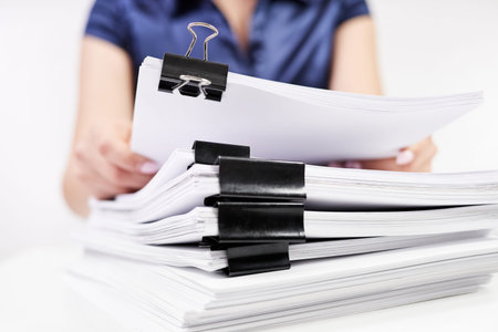 An office worker sorts out a stack of papers fastened with Binder Clips